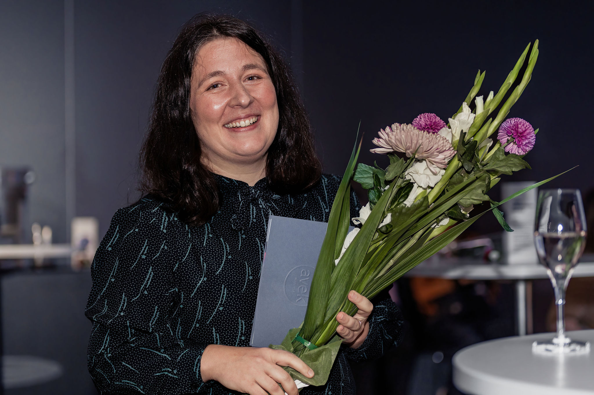 Azar Saiyar looking into the camera. She is holding a bouquet.