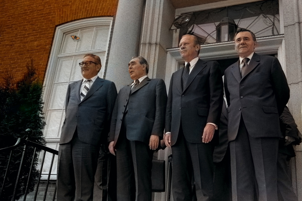 Four men dressed in suits standing in front of a building.