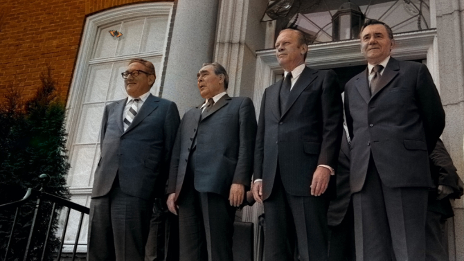 Four men dressed in suits standing in front of a building.