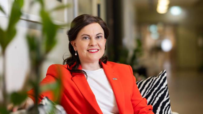 Ministeri Mari-Leena Talvitie katsoo kameraan ja hymyilee.